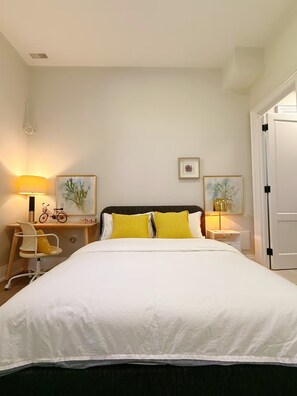 Een keurig opgemaakt hotelkamer met een bed, twee nachtkastjes, een stoel en een bureau.