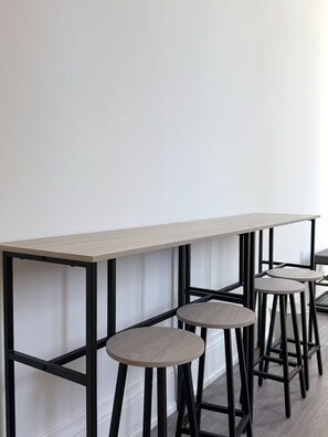 Een bar met een lange tafel en drie krukken.