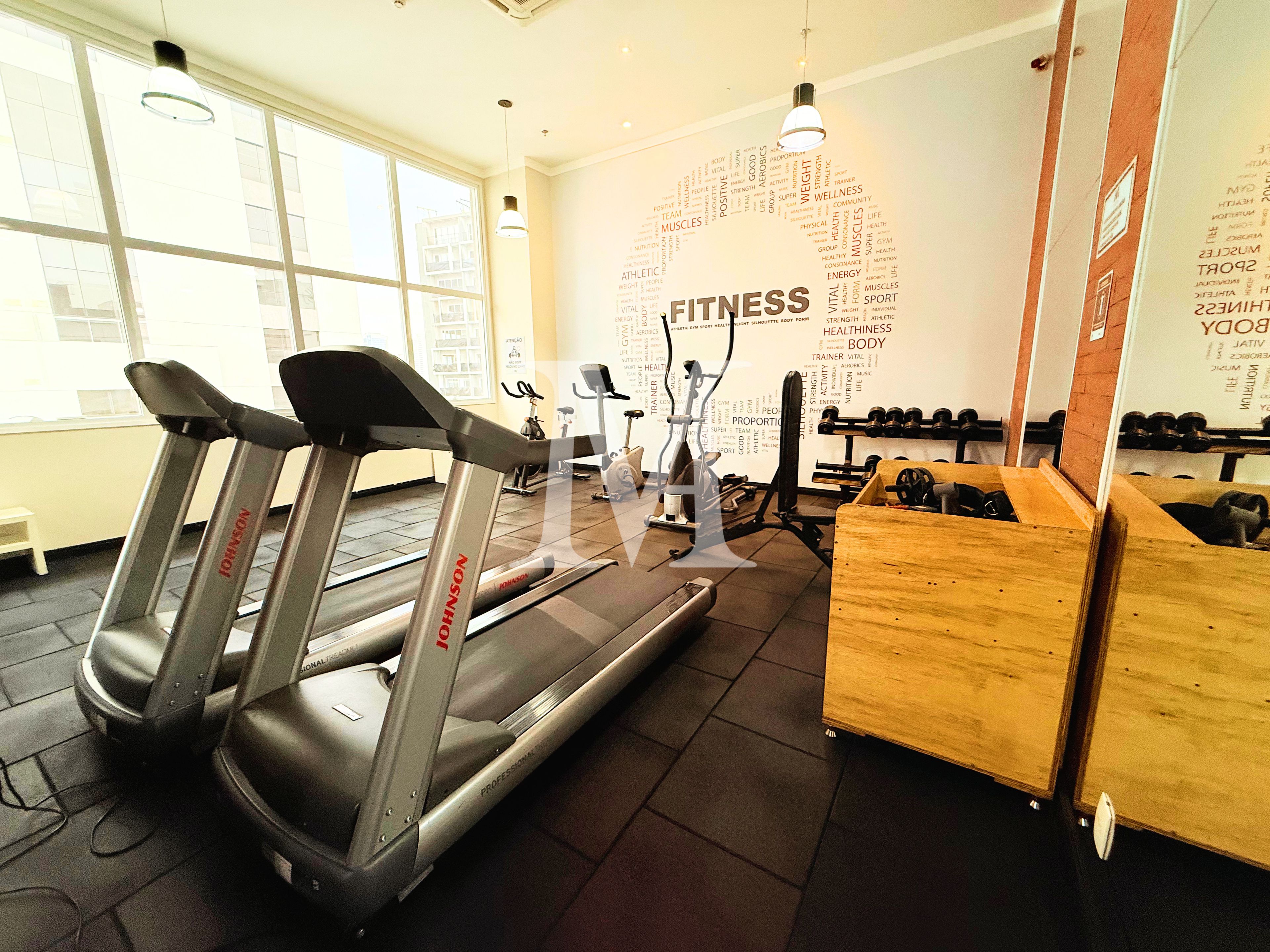 Un gimnasio con cintas de correr, bicicletas estáticas y pesas sueltas.
