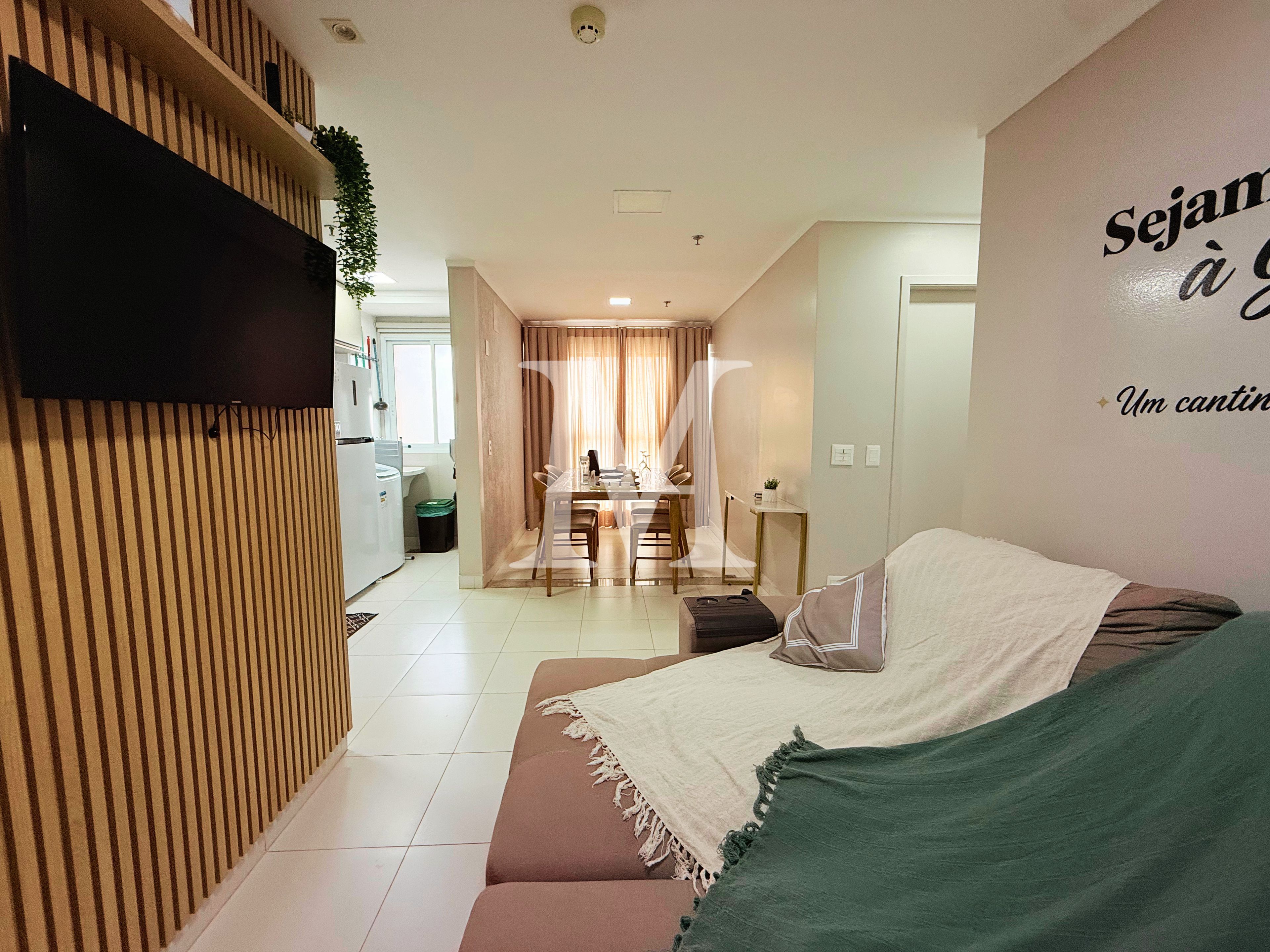 Ein modernes Wohnzimmer mit einer Couch, einem Essbereich mit Tisch und Stühlen sowie einer Küche im Hintergrund.