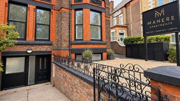 A brick building with a black metal gate and a sign for Manere Apartments.