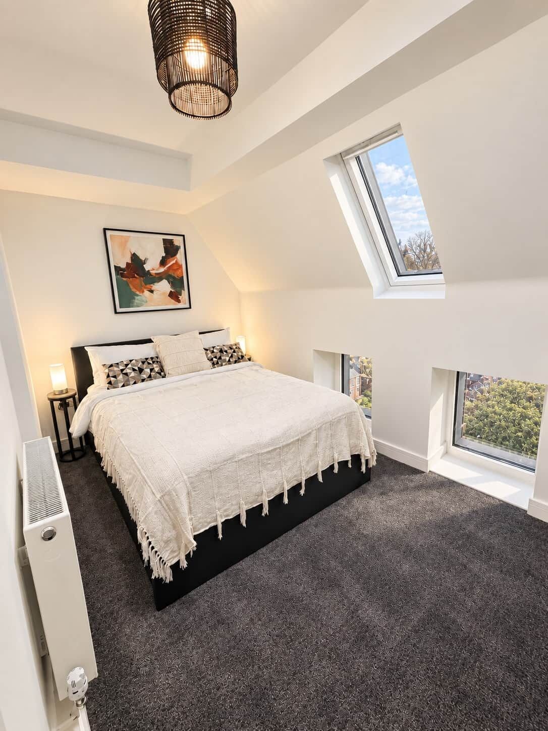 Un dormitorio con una cama grande, un tragaluz y vistas al exterior.