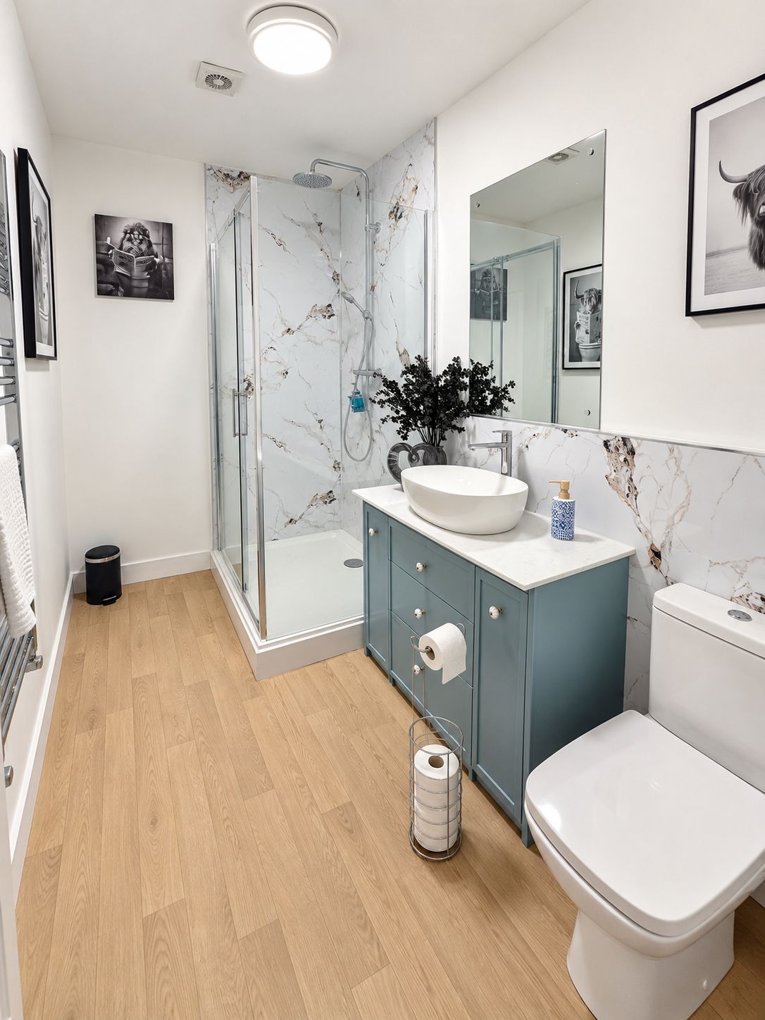 Un baño moderno con ducha envuelta en vidrio, un lavamanos blanco y un inodoro.