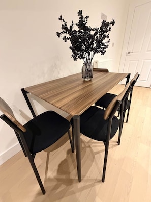 A dining table with a vase of flowers, four chairs, and a white door in the background. - King Bed • Free Parking • Stylish 1BR (Liverpool)