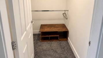 A narrow hallway with a wooden bench, a white door, and a hanging light fixture.