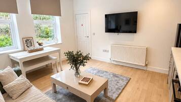 A modern living room with a sofa, coffee table, and a flat-screen TV mounted on the wall.