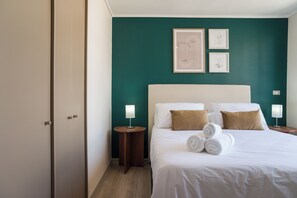 A hotel room with a bed, two bedside lamps, a nightstand, and a door. - Chic Ñuñoa Apt Cozy Stay for 5  (Ñuñoa)