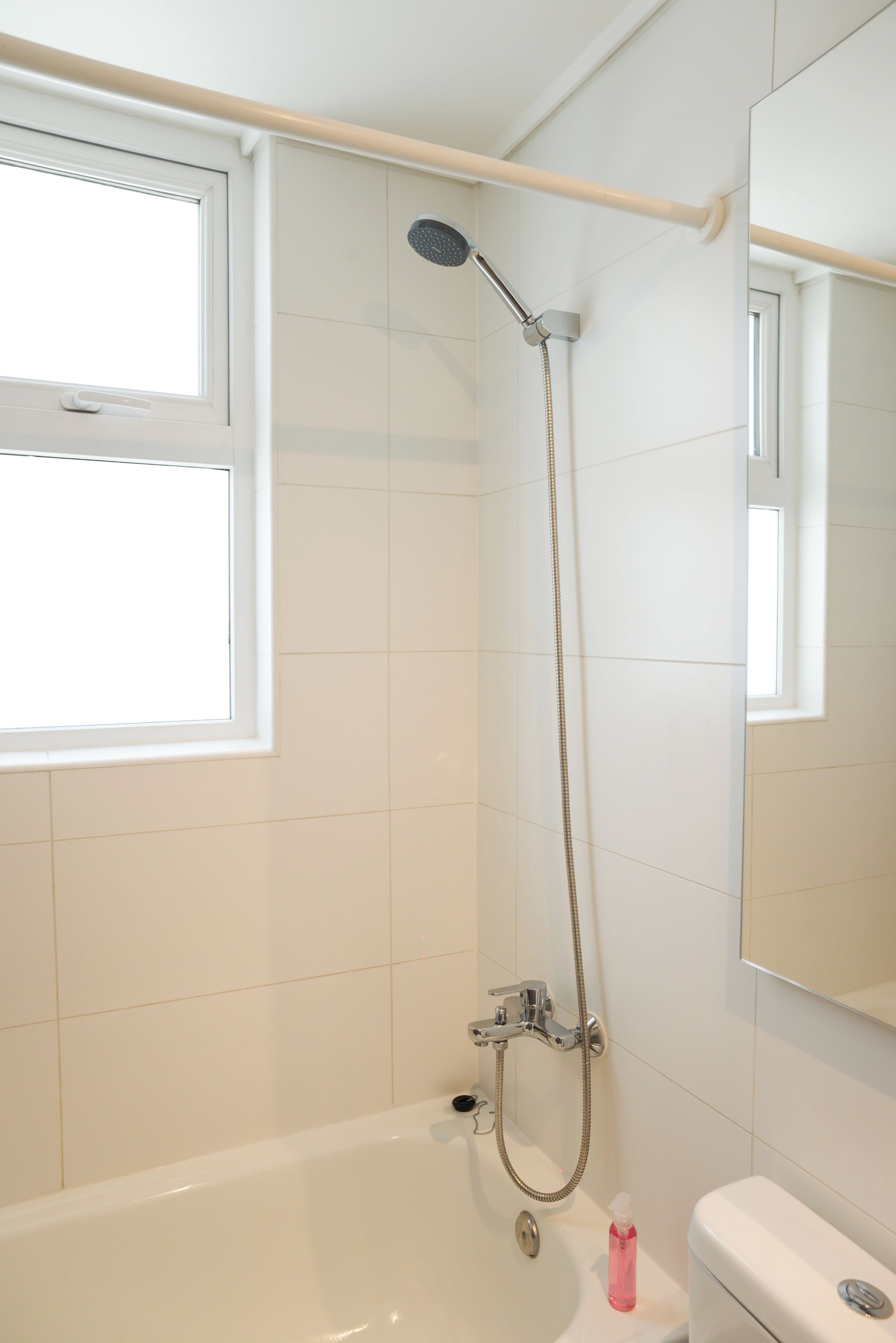 A bathroom with a bathtub, a shower, a toilet, and a window.