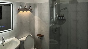 Uma casa de banho moderna com sanita, lavatório e chuveiro.