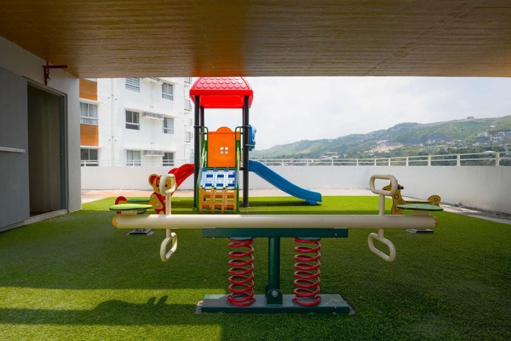 Een kinderspeelplaats met een wipkippen, glijbaan en klimconstructie.