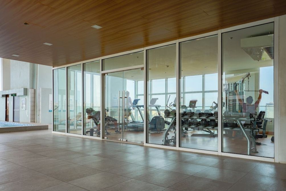 A spacious gym with exercise equipment, large windows, and a wooden ceiling.