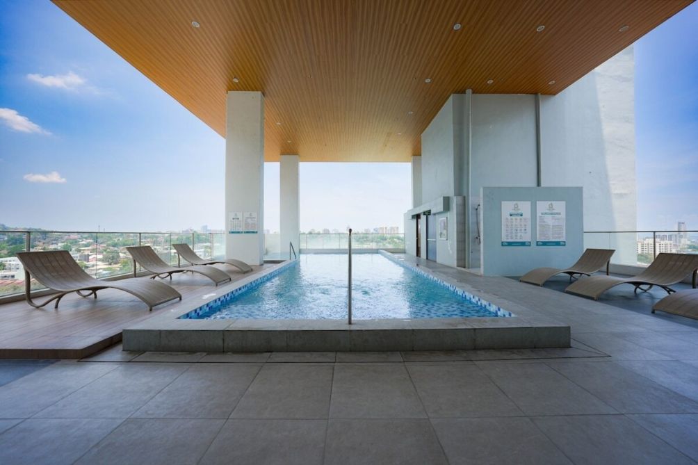 A rooftop pool with lounge chairs and a city view.
