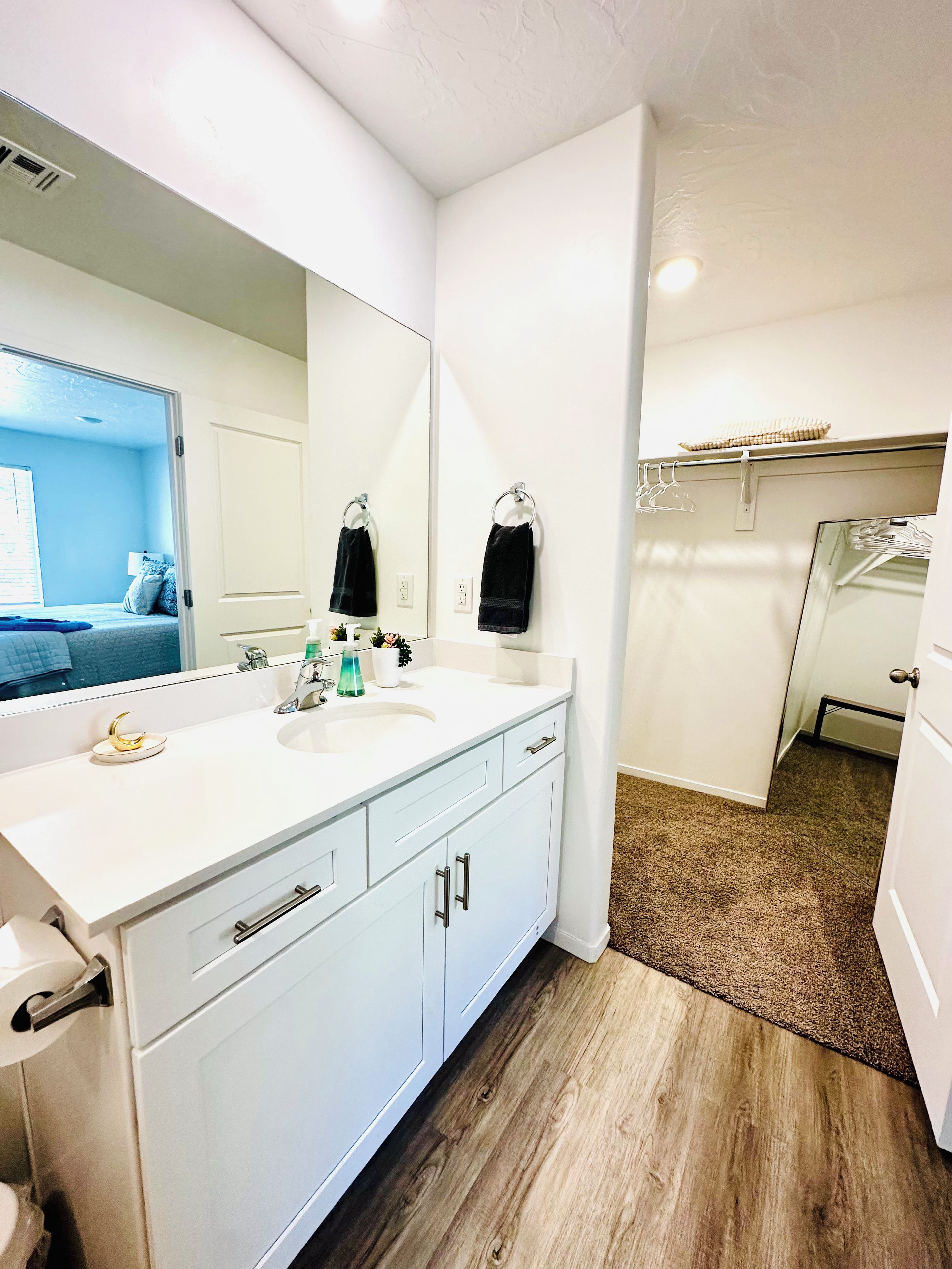 Une salle de bain avec un meuble-lavabo blanc, deux vasques, un miroir et un porte-serviettes.