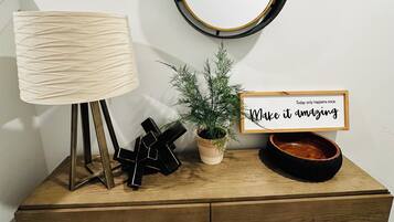 A wooden desk with a lamp, a potted plant, a mirror, and a motivational sign.