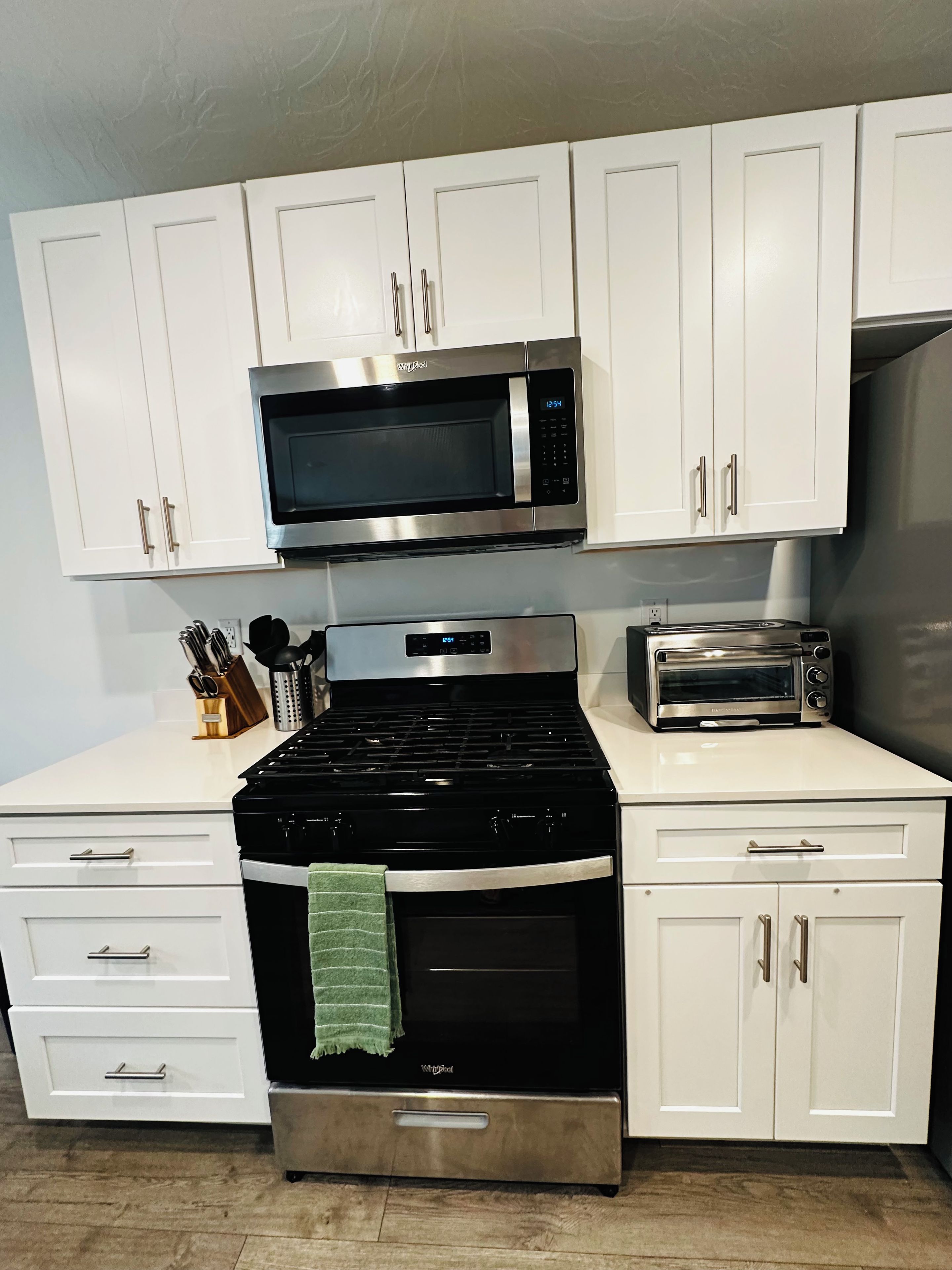 A kitchen with white cabinets, a microwave, a stove, and a toaster.
