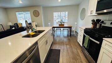 A modern kitchen with a central island, stainless steel appliances, and a dining area with natural light.
