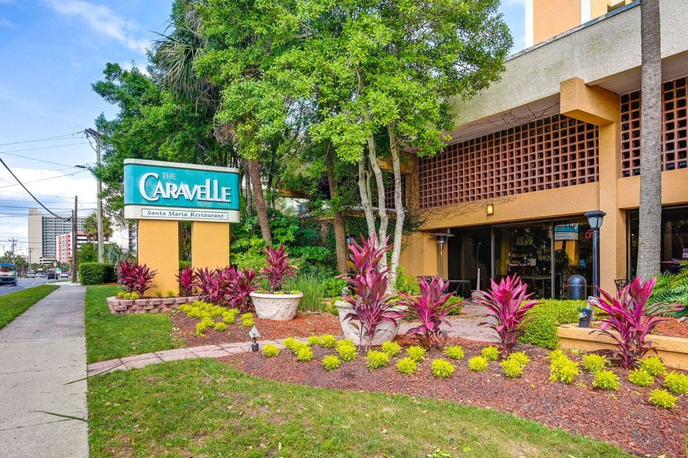 Señal de hotel para 'The Caravelle' con un jardín delantero.