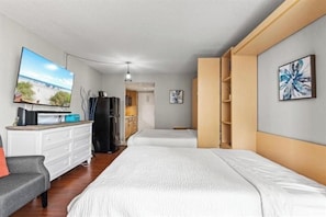 A hotel room with a bed, a TV, a dresser, and a view of the beach. - Caravelle Towers 331 (Myrtle Beach)