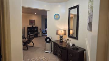 A hallway with a ceiling fan, a rug, a dresser, and a mirror.