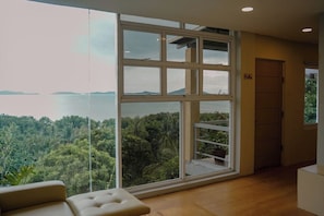 Una habitación con un ventanal que ofrece vistas a un área boscosa y un cuerpo de agua.