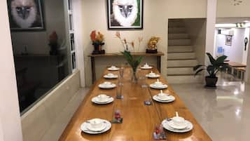Een lange eettafel gedekt voor een maaltijd, met borden, glazen en een bloevas.