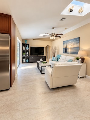 A modern living room with a sofa, a coffee table, and a television. - 3-bedroom house in gorgeous Cape Coral with pool and deck (Cape Coral)