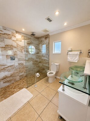 A bathroom with a glass shower enclosure, a toilet, a glass sink, and a towel rack. - 3-bedroom house in gorgeous Cape Coral with pool and deck (Cape Coral)