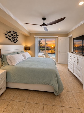 A bedroom with a bed, a ceiling fan, a view of a swimming pool, and a TV on a cabinet. - 3-bedroom house in gorgeous Cape Coral with pool and deck (Cape Coral)