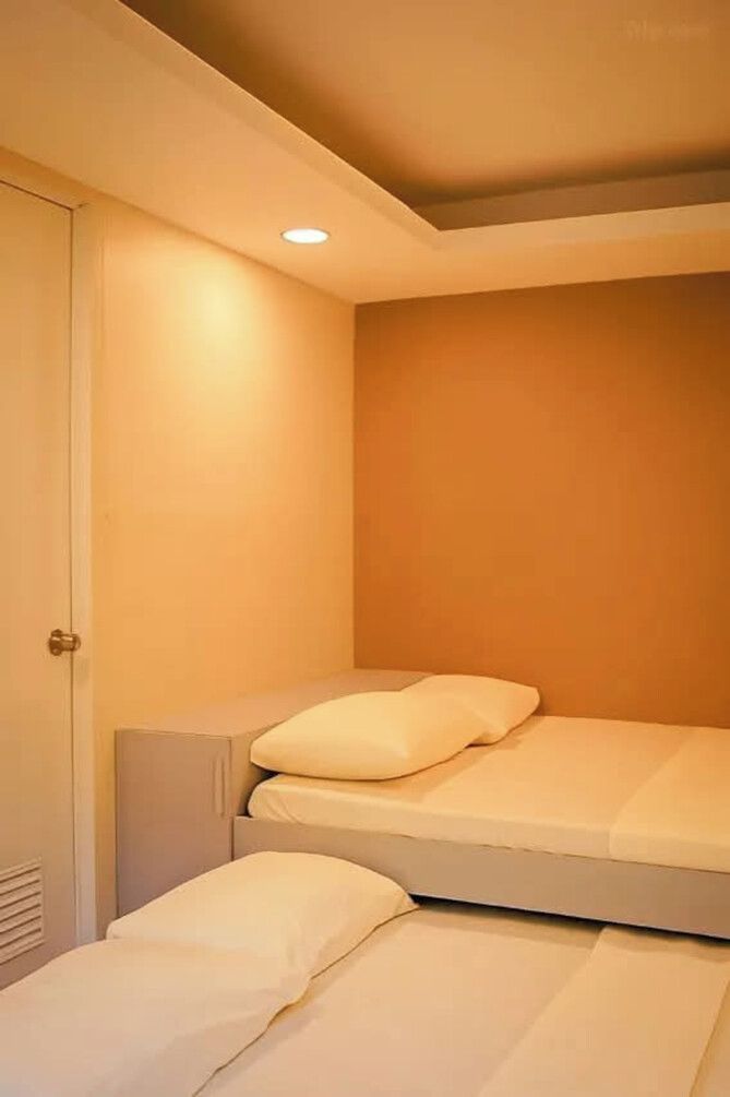 A small, single-bed room with a door and a light fixture on the ceiling.