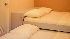 A small, single-bed room with a door and a light fixture on the ceiling.