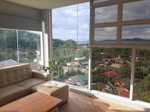 A room with a large window, a sofa, and a wooden table.