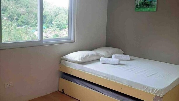 A single bed with a mattress and pillows in a room with a window and a painting on the wall.