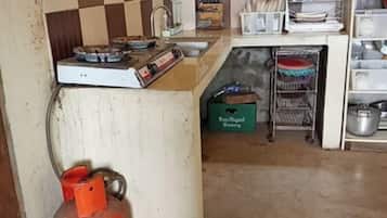 Ett kök med en gasspis, upphängda köksredskap och en gastub.