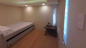 Een kleine kamer met een bed, een bureau en een raam met zonwering.