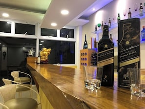Un espace bar avec un comptoir en bois, deux bouteilles de Johnnie Walker Double Black et une statue dorée.
