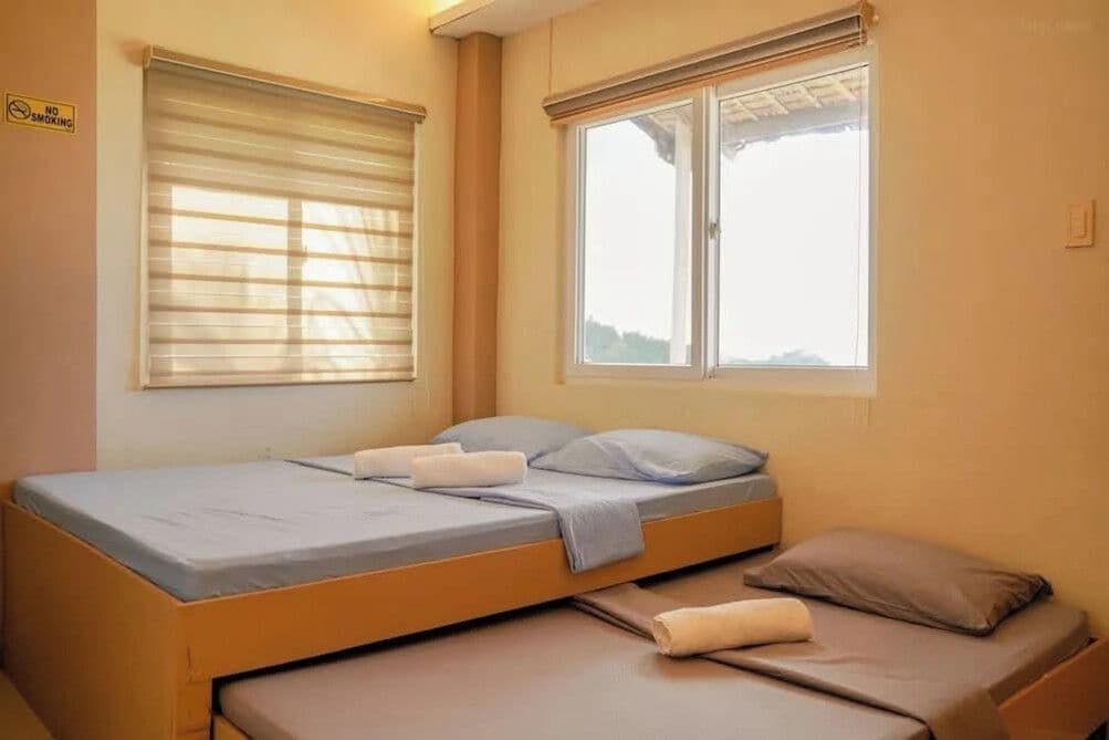 A single-bed room with a window, a 'No Smoking' sign, and a view of the outdoors.