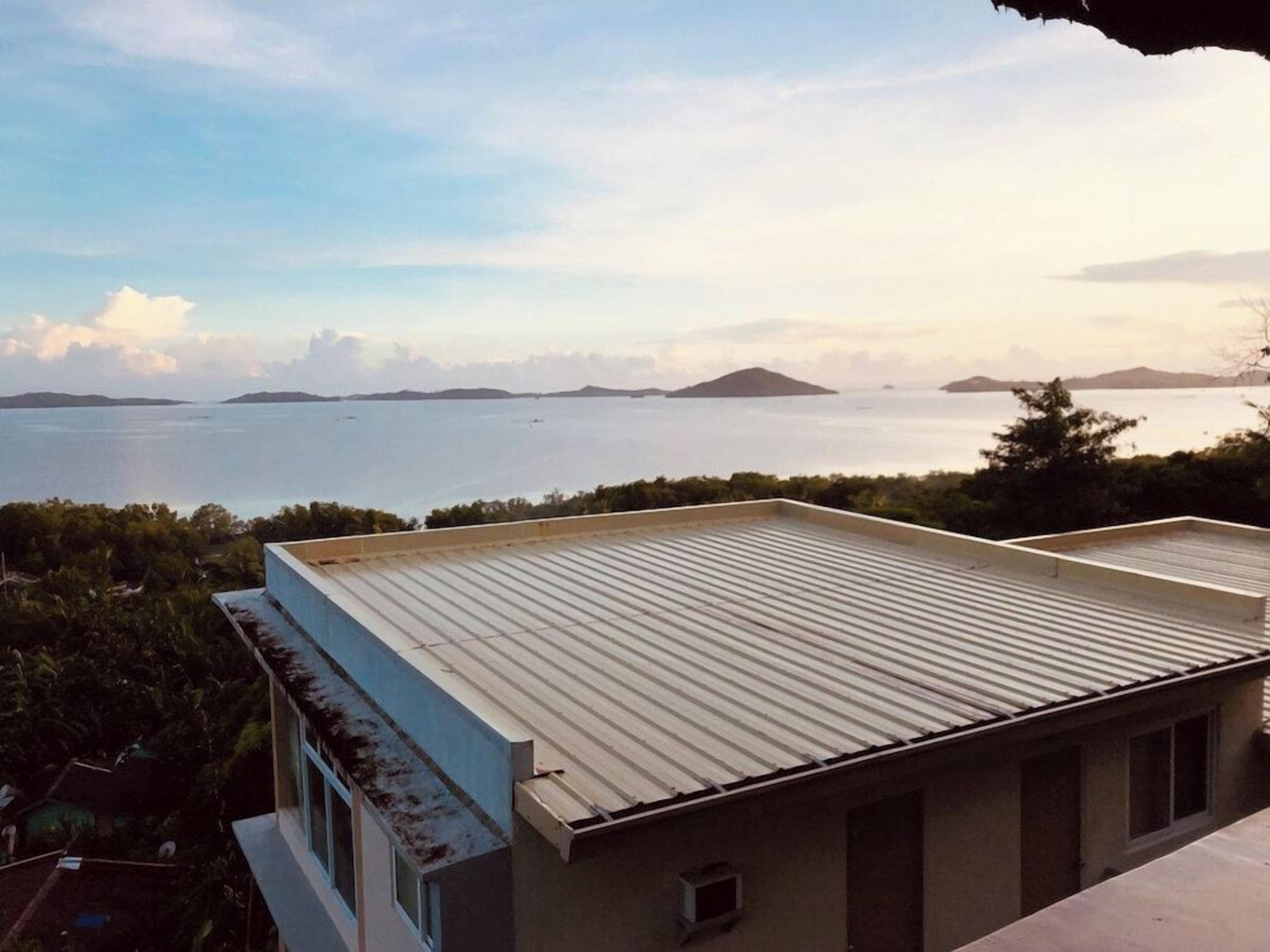 A building with a flat roof overlooking a body of water and distant landforms.