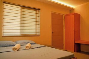 Una habitación con una cama, una ventana con persianas, una puerta y un armario de madera.