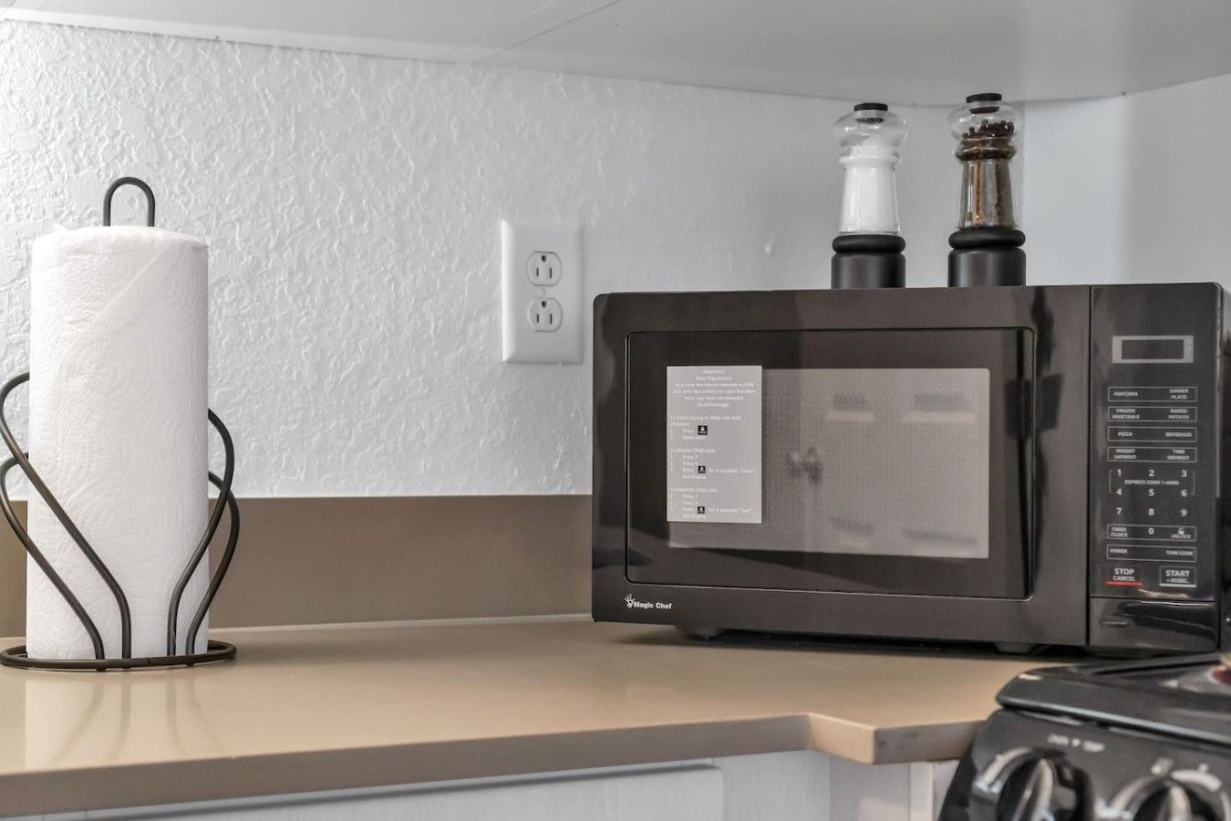 A kitchen with a microwave, a paper towel holder, and a stove.
