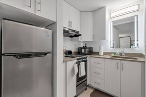 A modern kitchen with a stainless steel refrigerator, a microwave, an oven, and a sink with a mirror above it. - Dreamy Disney Retreat + Free Parking & Pool (Kissimmee)