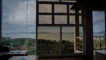 Een kamer met een groot raam, met uitzicht op een wateroppervlak en het verre land.