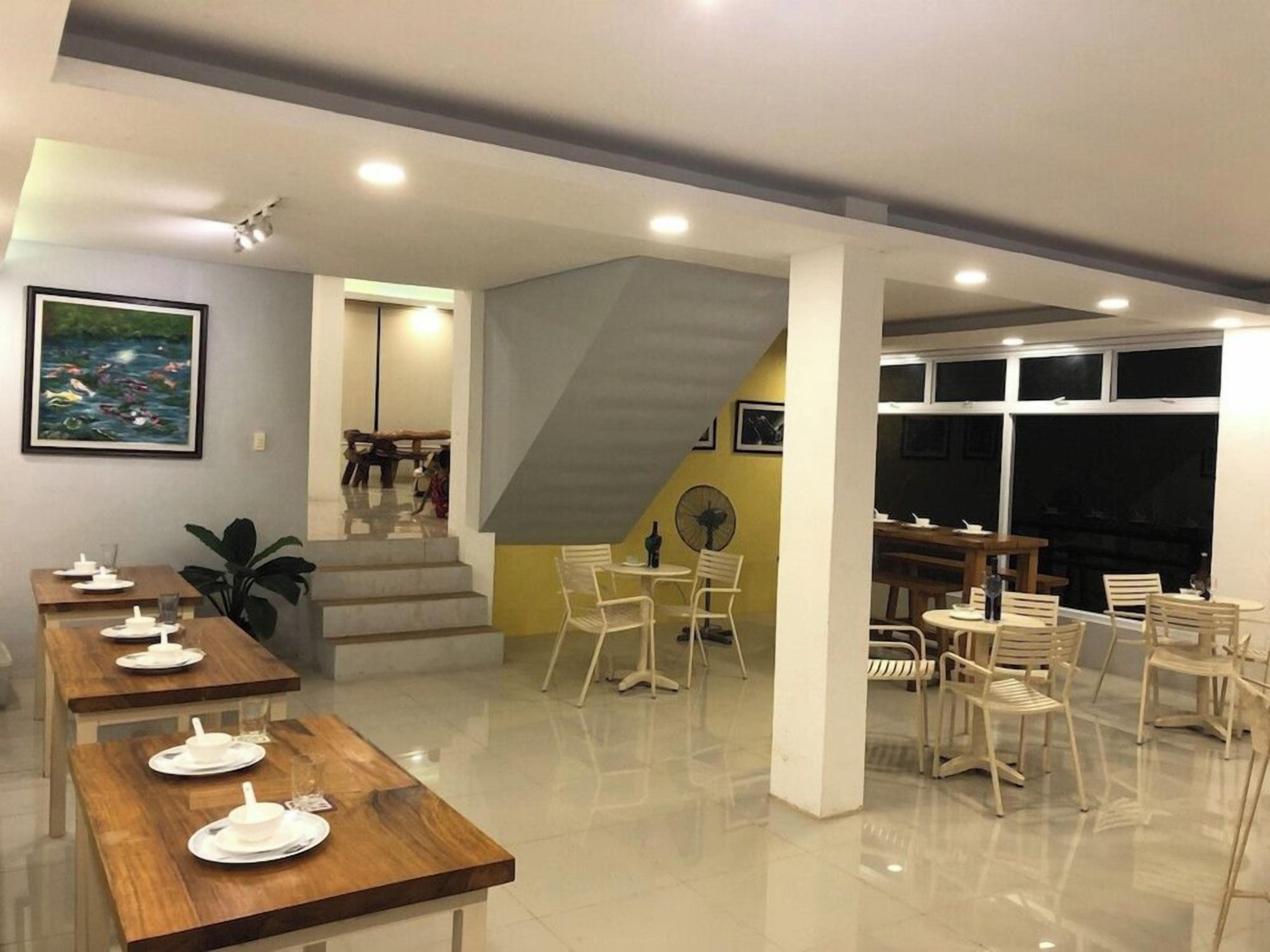 A dining area with multiple tables and chairs, a staircase, and a fan.