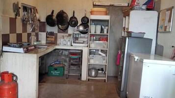 A compact kitchen with basic amenities, including a sink, a refrigerator, and a gas cylinder.