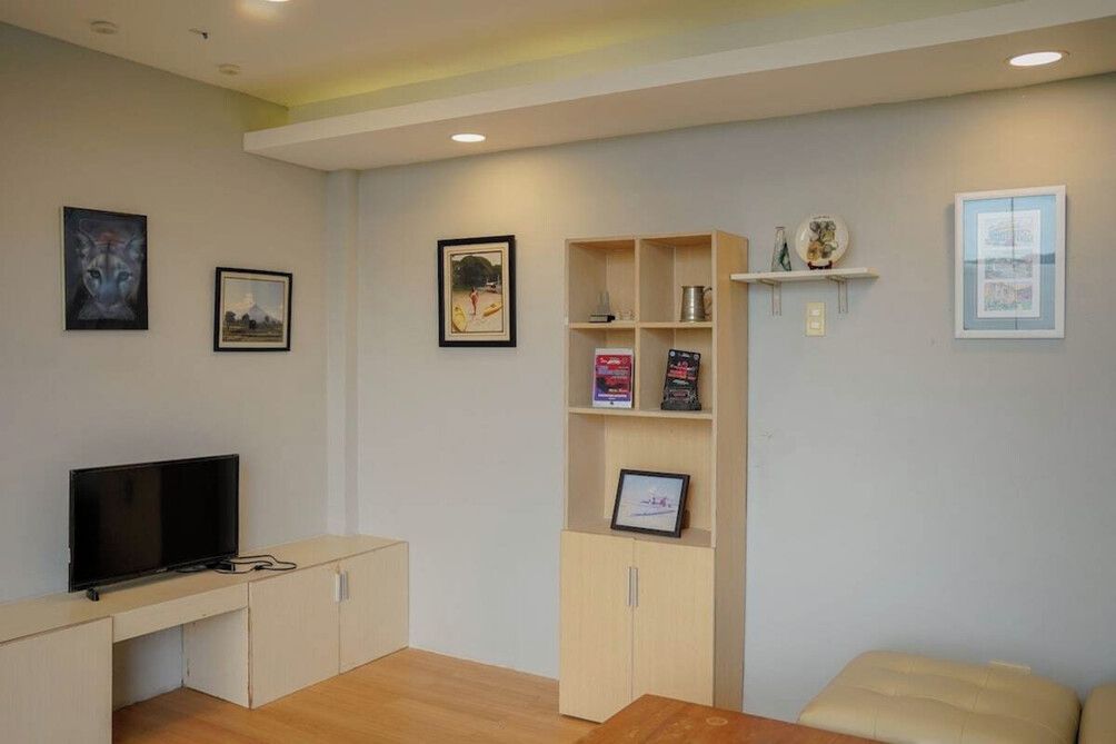 Un salon équipé d’un téléviseur à écran plat, d’un meuble en bois, d’une bibliothèque et d’un banc rembourré.