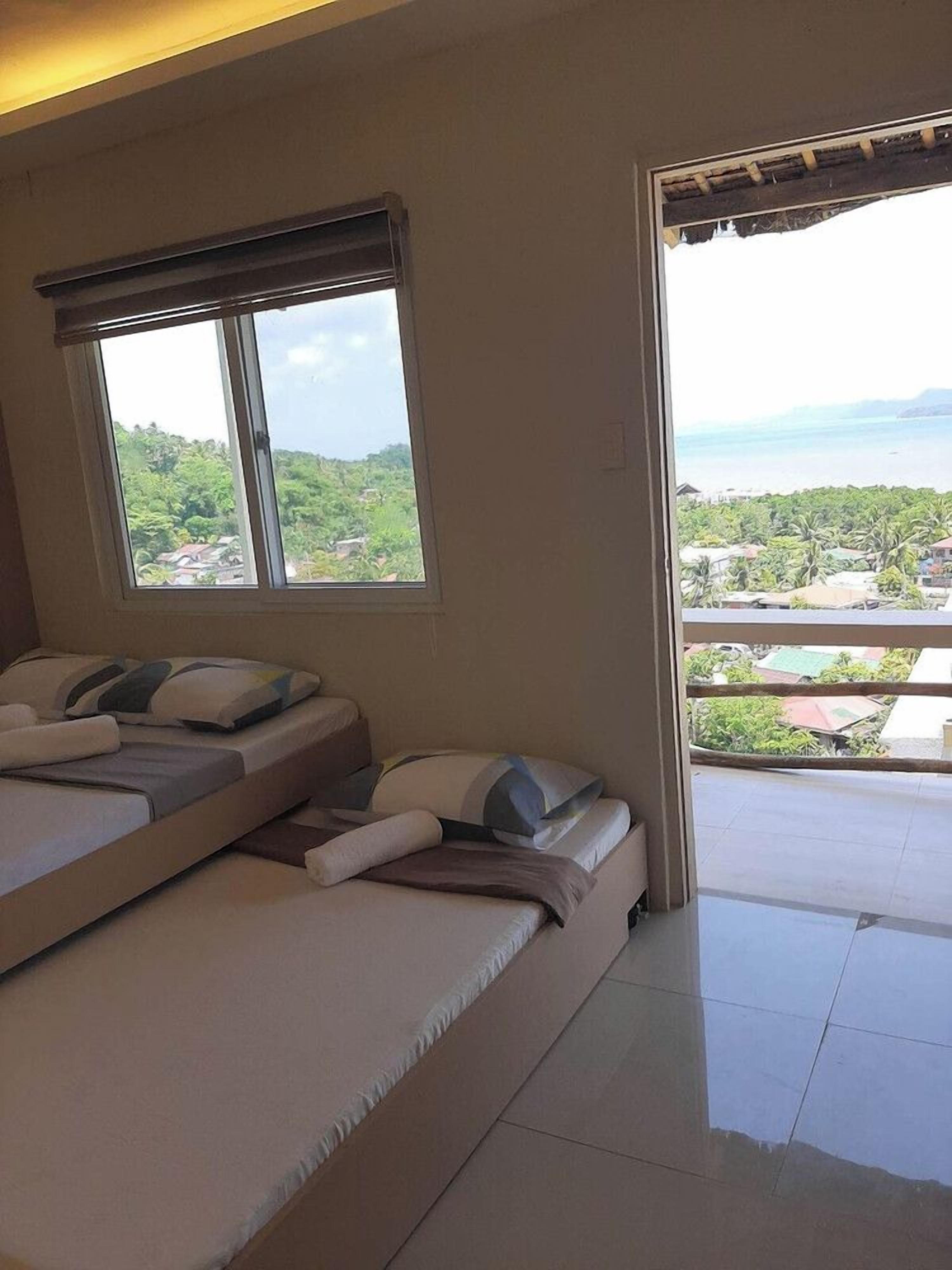 A bedroom with two beds, a view of the sea, and a balcony.