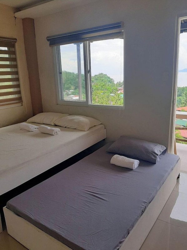 Una habitación con cama, ventana y vista al verdor exterior.