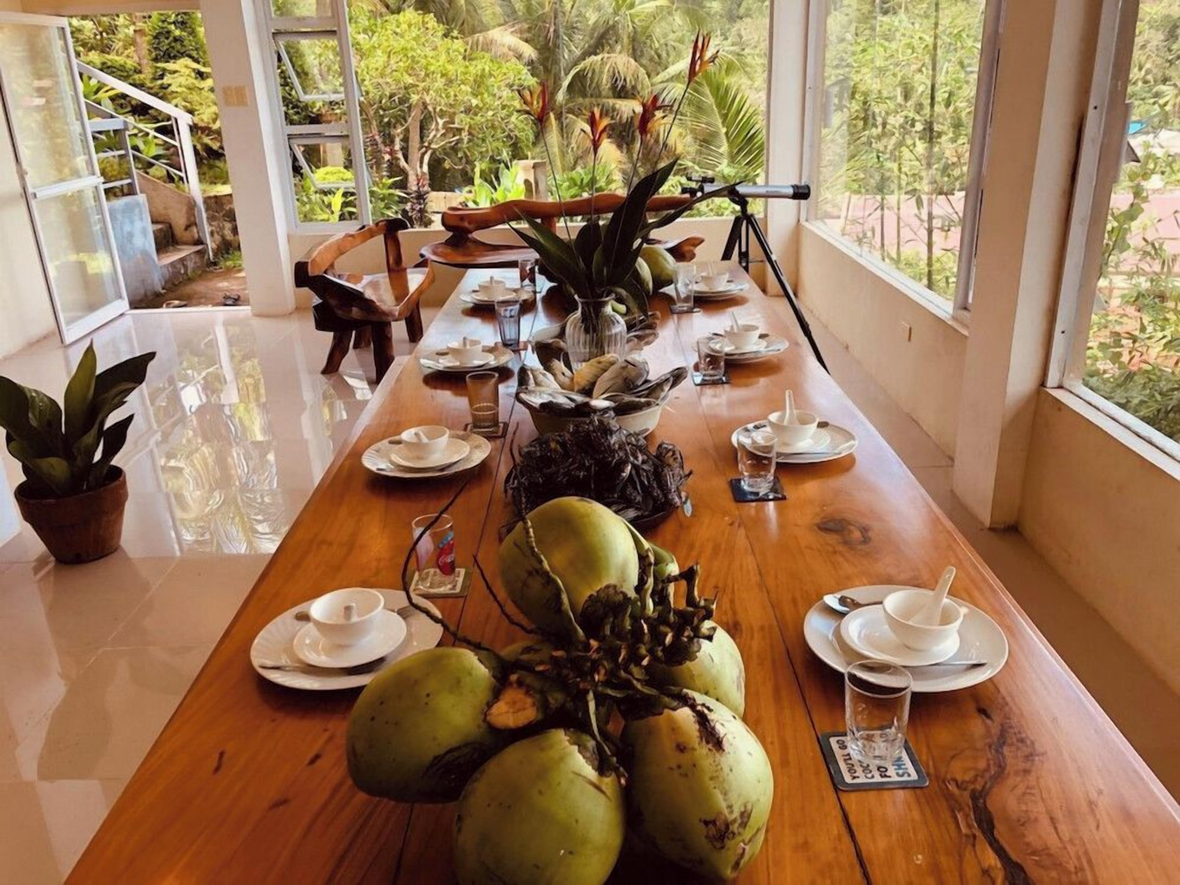 A dining table set with plates, cups, and a large centerpiece of coconuts.