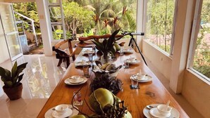 A dining table set with plates, cups, and a large centerpiece of coconuts. - Cozy Room at Mamima BnB (Caramoan)