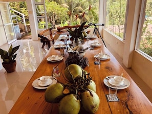 Una mesa de comedor dispuesta con platos, tazas y un gran centro de cocos.