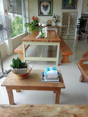 A dining area with a wooden table, a potted plant, and a fan.